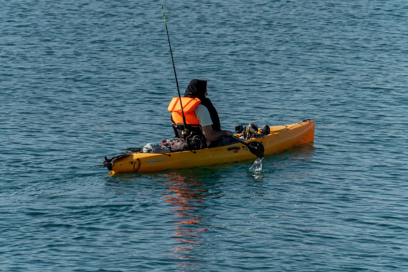 Yellow kayak on calm sea with paddler seen from behind