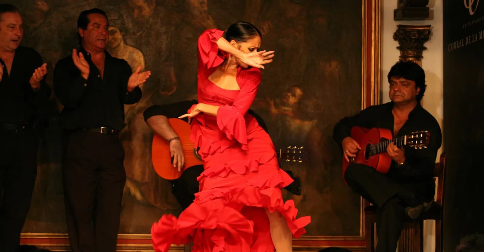 Flamenco dancer in a red dress with guitarists at Corral de la Morería in Madrid