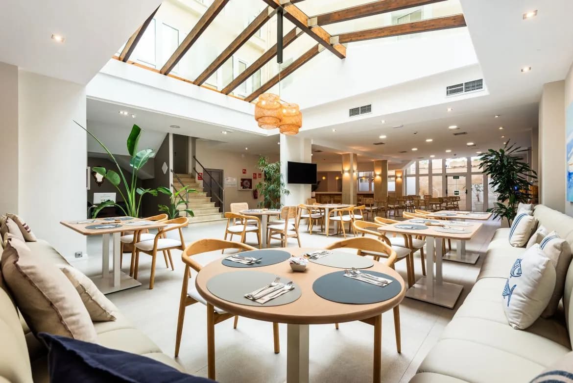 Bright lounge with tables and sofas at Hotel Menorca Patricia in Ciutadella