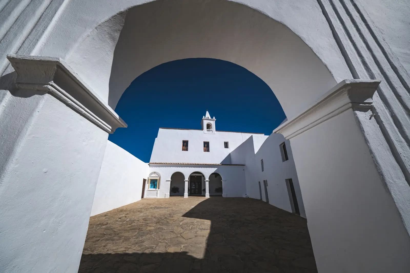 Whitewashed historic church courtyard framed by a white arch