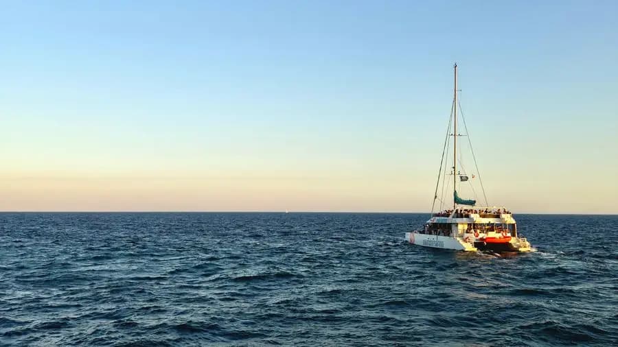 Passenger catamaran at sunset over a calm sea