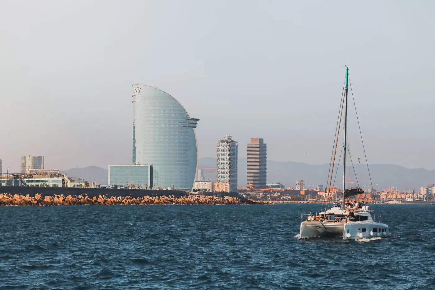 Barcelona's coastal skyline with a sailing boat on a sunny day