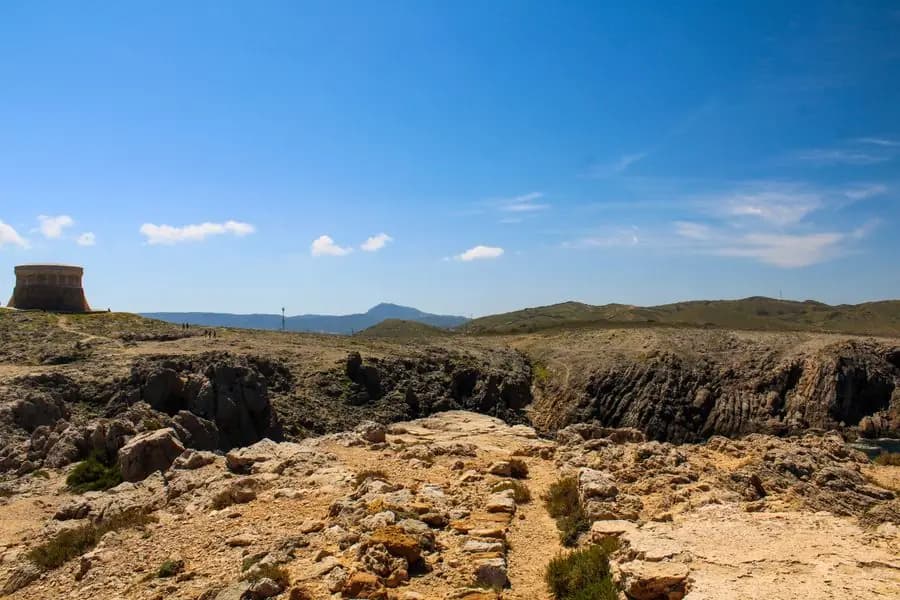 Stone tower above the cliffs under a blue sky in Menorca