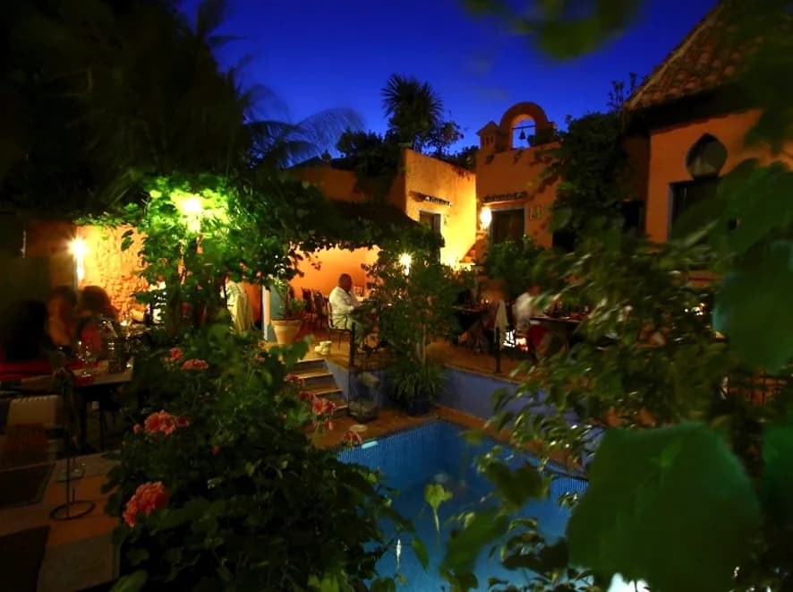 Illuminated evening terrace around a pool and flowering gardens