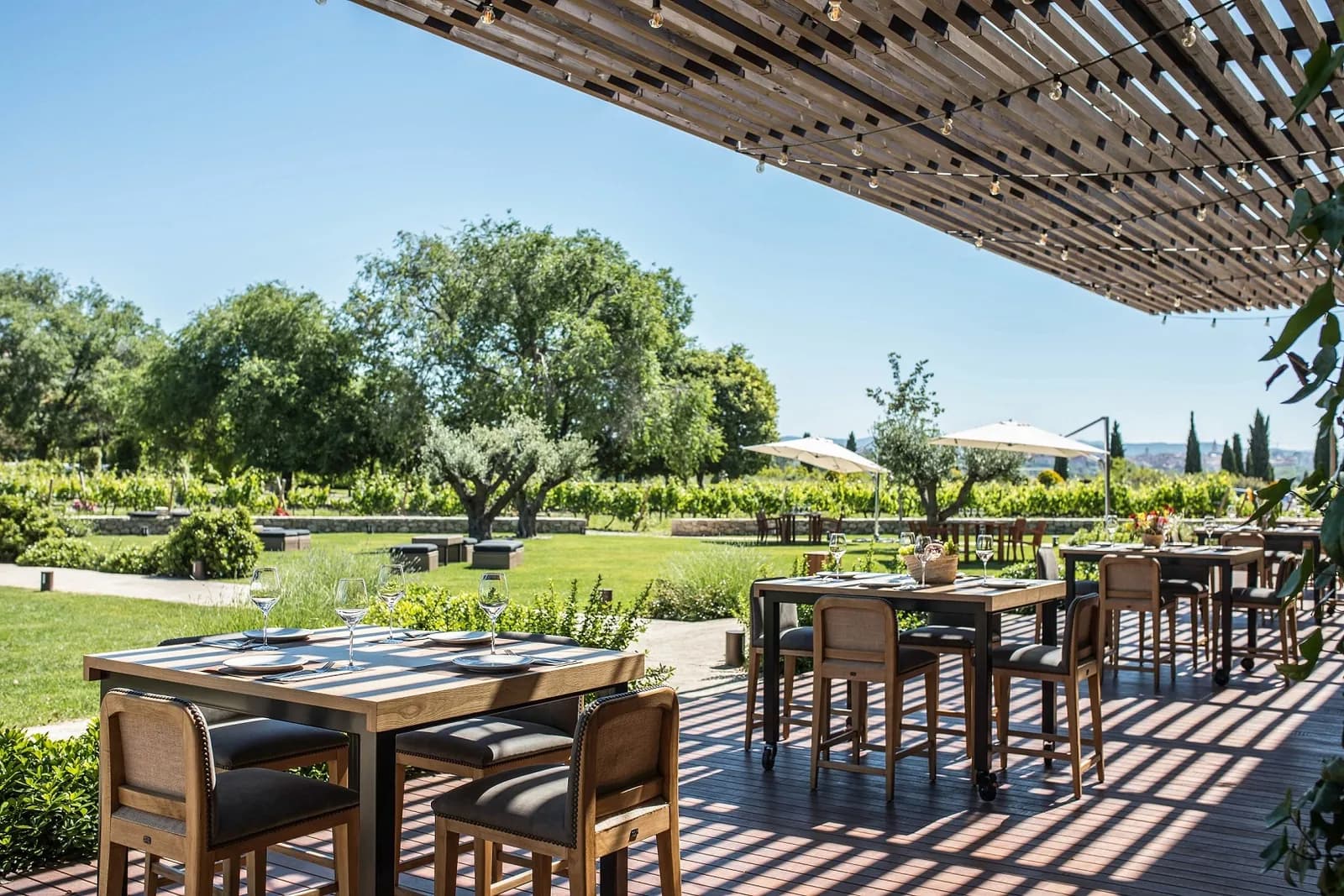 Terrace of El Celleret restaurant among vineyards and trees, tables under a pergola