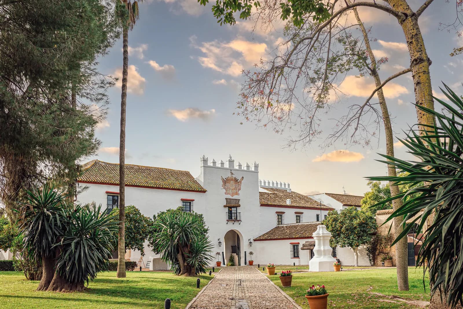 White façade of Hacienda Benazuza in Sanlúcar with palms and gardens