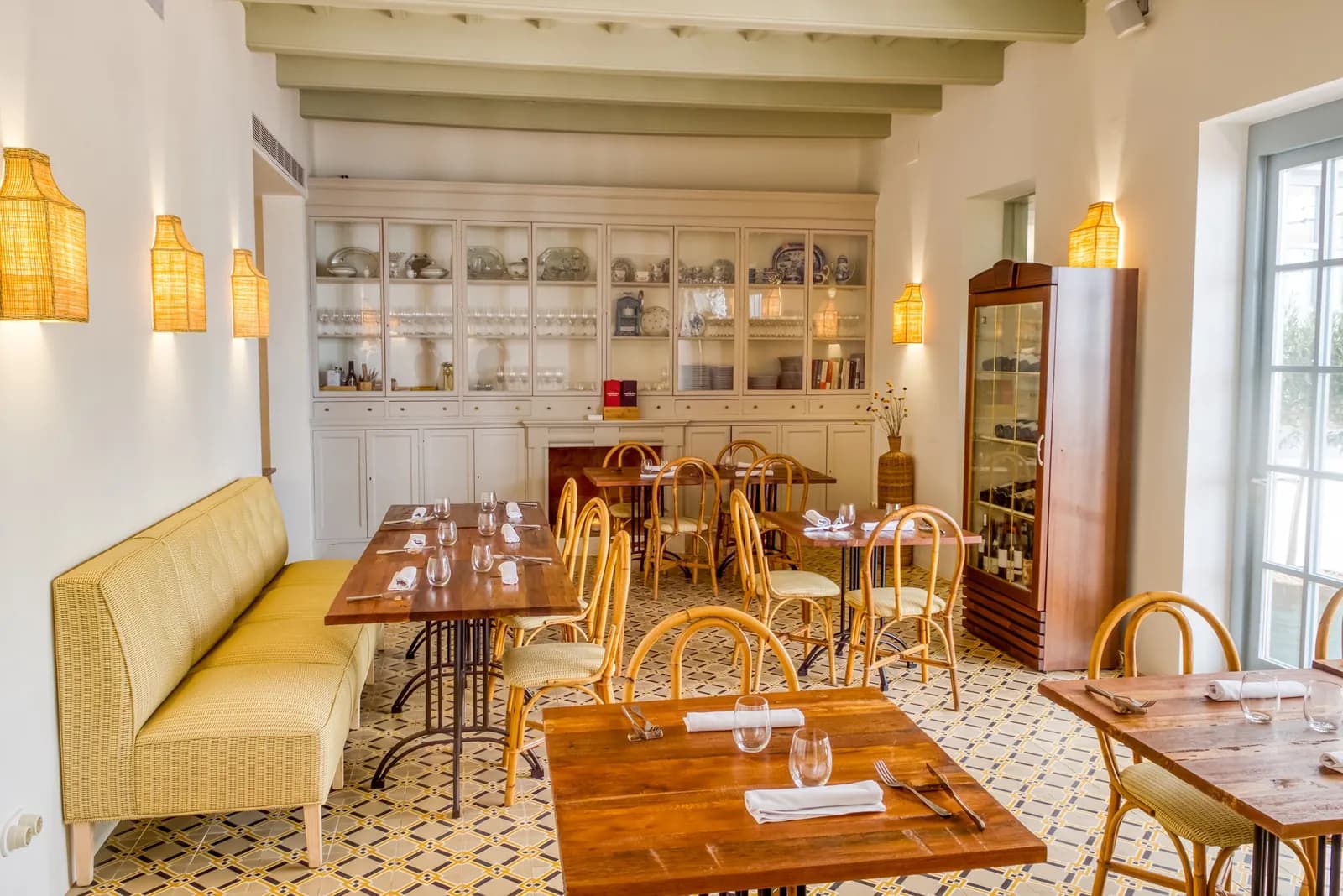 Bright room with yellow banquettes and wooden tables at Ses Forquilles in Mahón