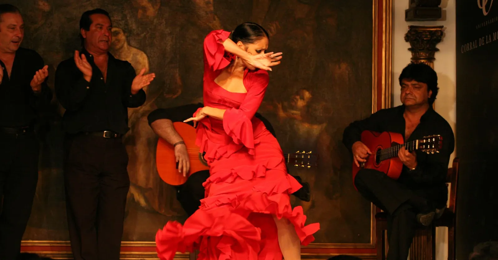 Flamenco dancer in a red dress with guitarists at Corral de la Morería in Madrid