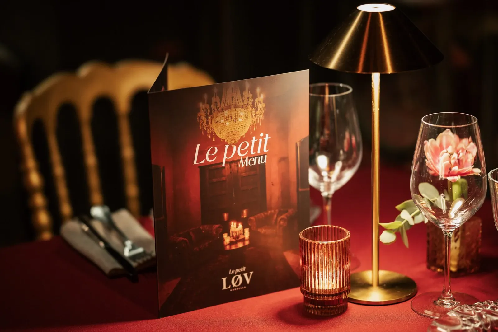 Menu and gold table lamp on a red tablecloth at LØV Marbella