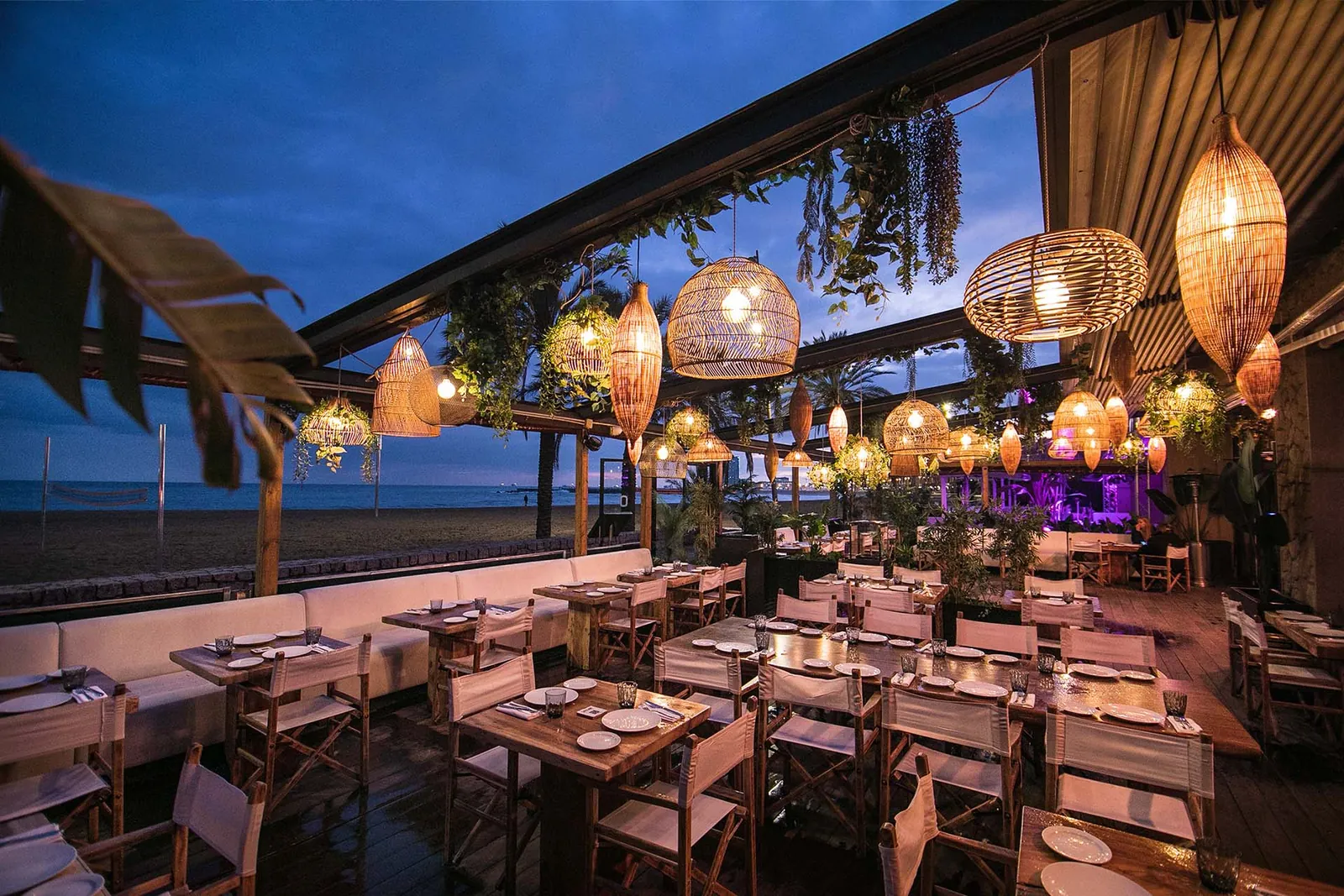 Opium Barcelona restaurant room in the evening with wicker pendant lights and laid tables