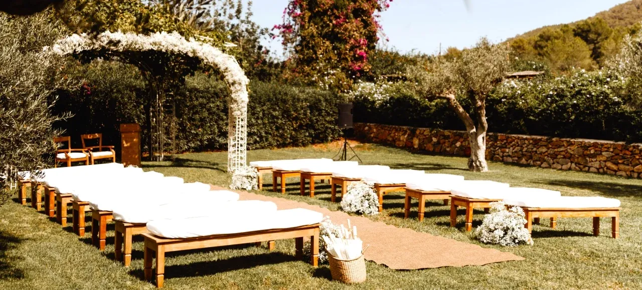 Outdoor ceremony space at Atzaro hotel in Ibiza with white benches and flower arch