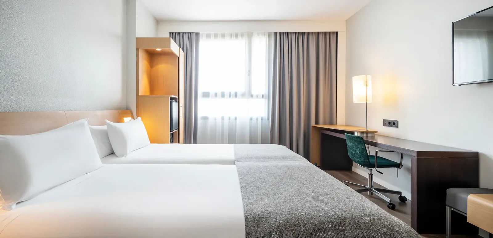 Guest room at Ilunion Valencia 4 hotel with large white bed and desk in Valencia