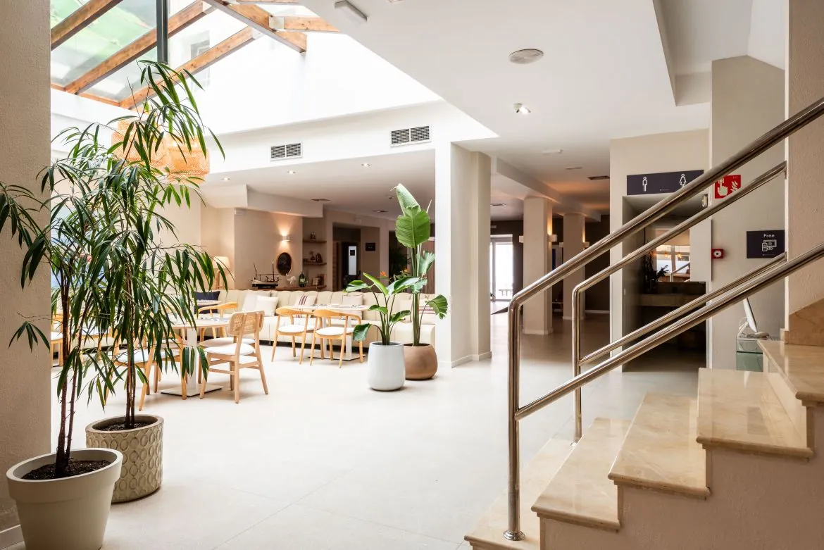 Bright glass-roofed atrium with plants at Hotel Menorca Patricia in Ciutadella