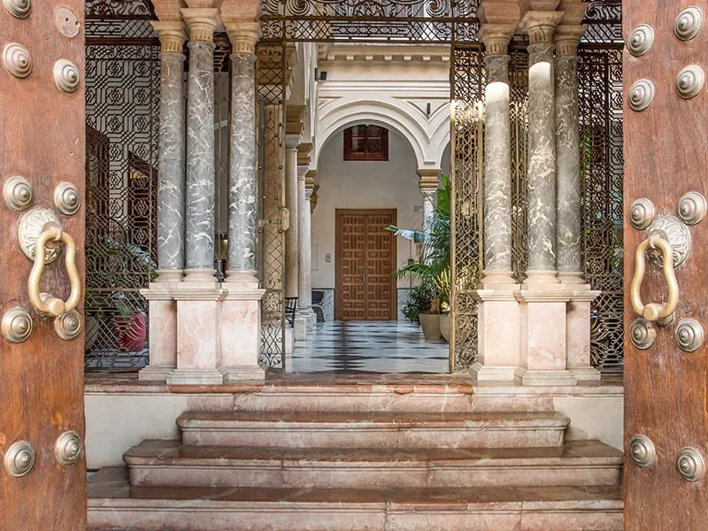 Entrance of Palacio de Villapanés in Seville with carved wooden doors and columns