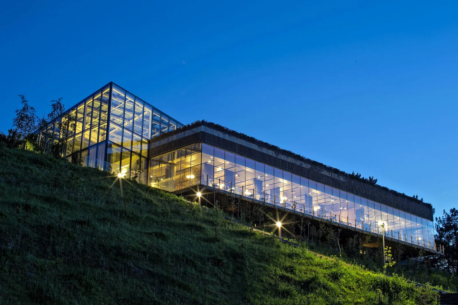 Glass facade of Azurmendi lit at dusk on a hillside in Larrabetzu