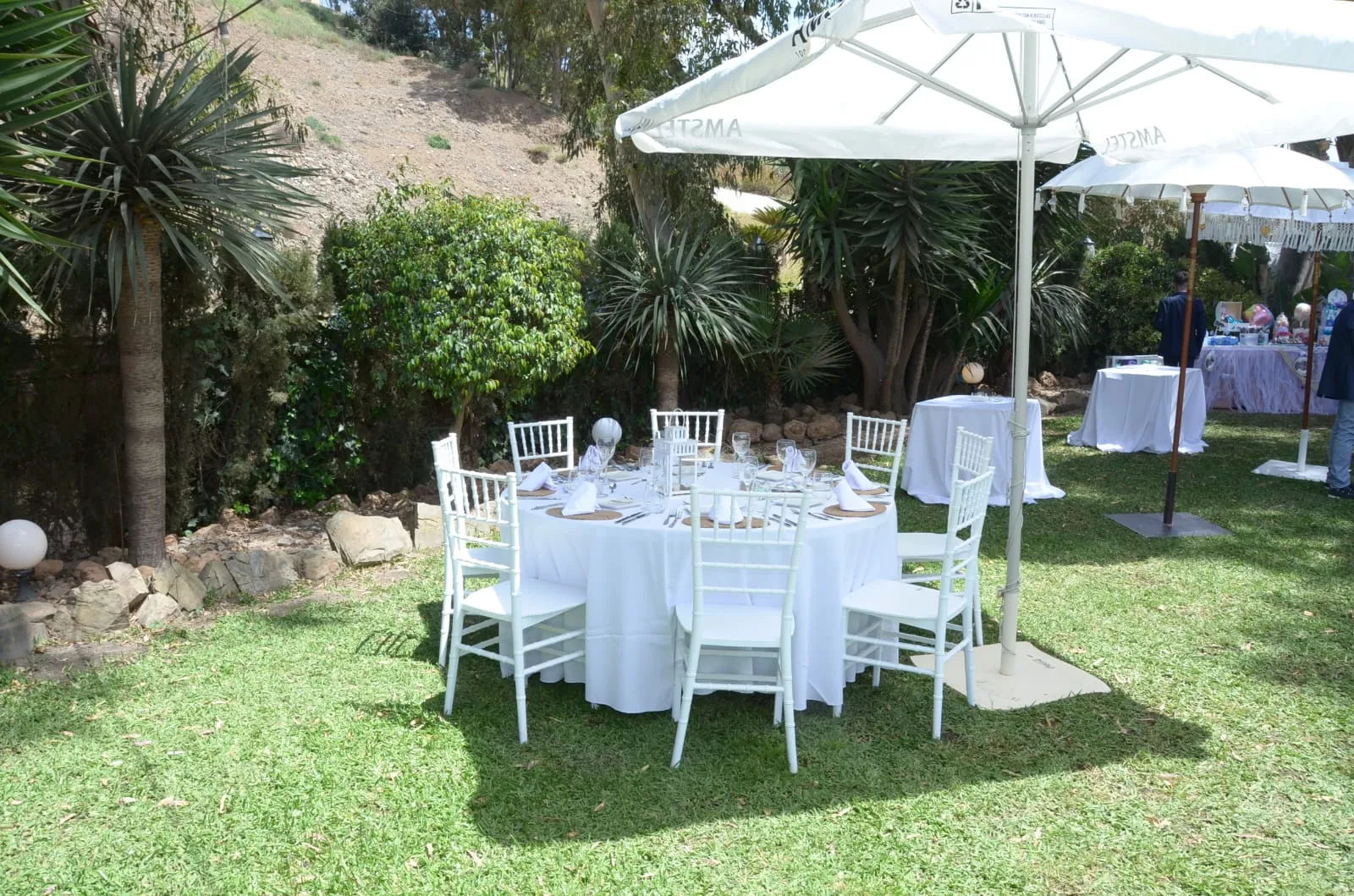 Garden of Cortijo San Joaquín in Malaga with round tables under white parasols