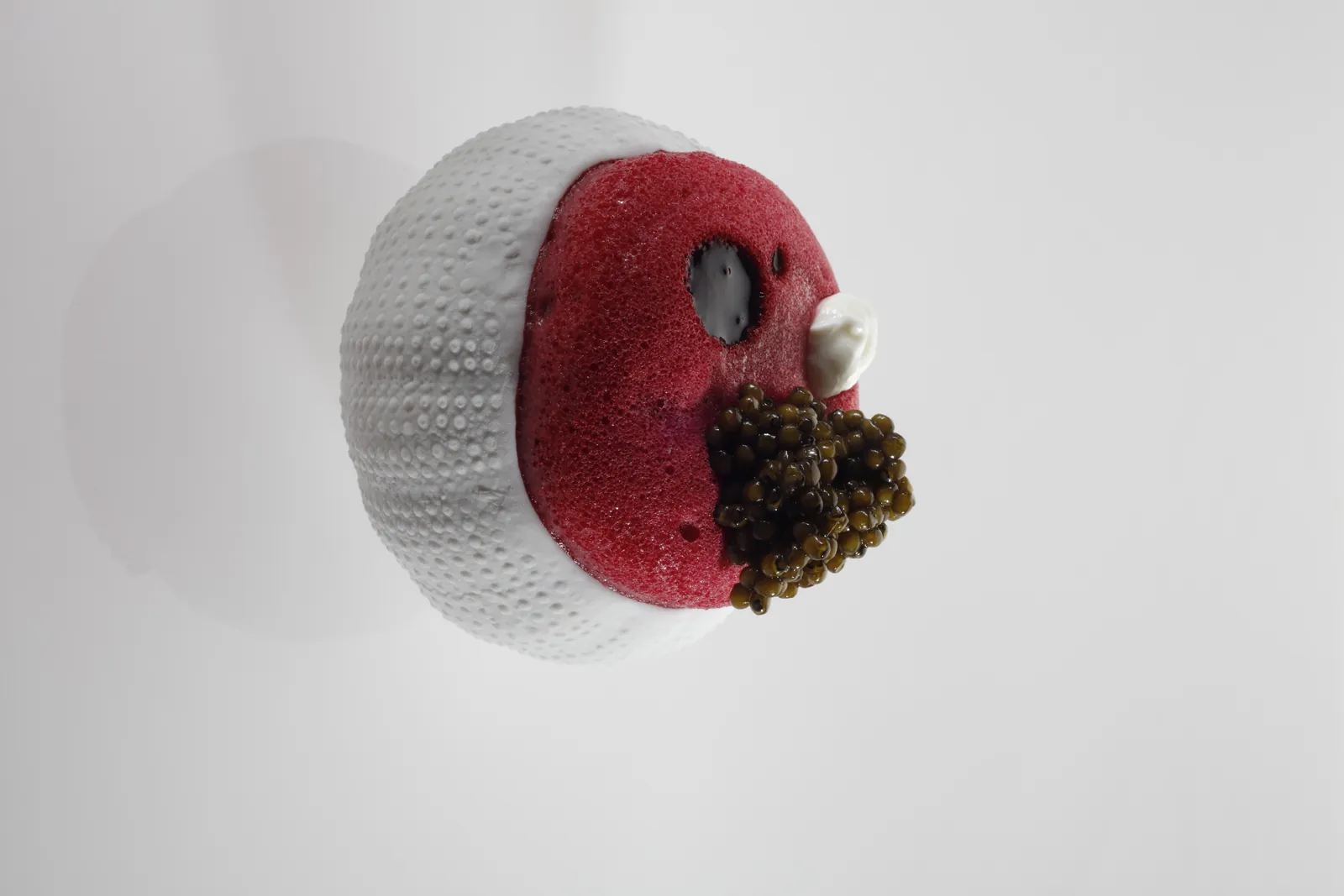 Gastronomic creation at Disfrutar restaurant in Barcelona, white and red sphere on pale background