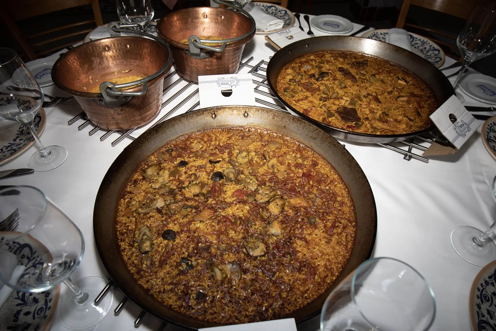 Paellas and copper pots served at a table in La Pepica, Valencia
