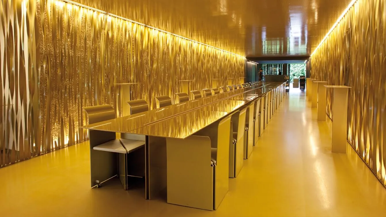 Dining hall of Les Cols restaurant in Olot with long table and lit wood walls
