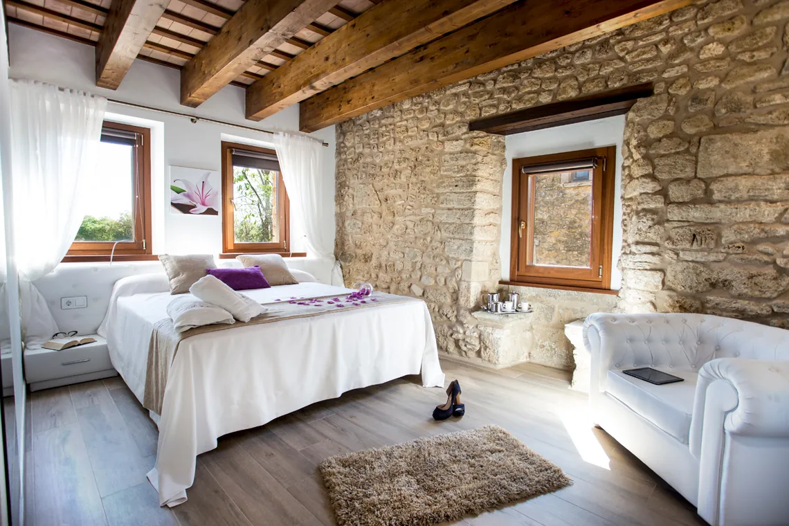 Double bedroom with exposed stone wall and beams