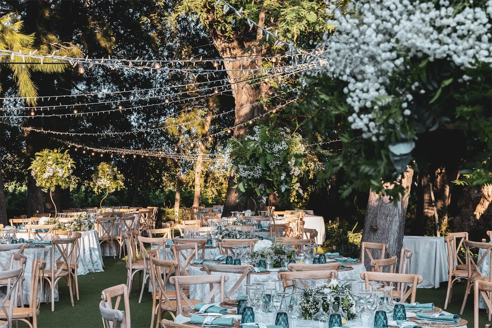 Tables set in the villa garden, lit by string lights